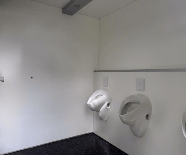 Drei Urinale im Herrenbereich des Toilettenwagens Deluxe mit Spiegel und Oberlicht