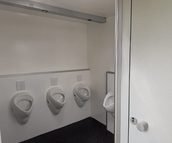 Herrenbereich eines mobilen Toilettenwagens mit sechs Urinalen und einer separaten WC-Kabine, angeboten von PZV Elting aus Emsdetten.