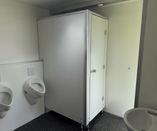 Innenansicht des Herrenbereichs eines mobilen Toilettenwagens mit zwei Urinalen, einer WC-Kabine und einem Waschbecken – PZV Elting, Emsdetten.