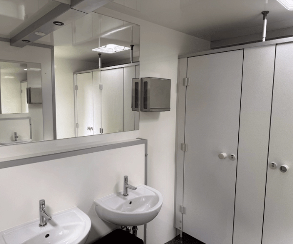 Moderner Toilettenwagen mit zwei Waschbecken, Spiegeln und separaten WC-Kabinen im Damenbereich, angeboten von PZV Elting aus Emsdetten