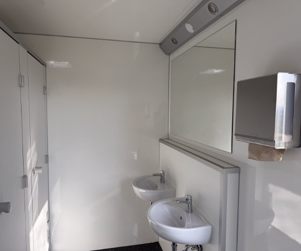Zwei moderne Waschbecken mit Spiegel, Seifenspender und Papierhandtuchspender im Damenbereich des Toilettenwagens 4&1 von PZV Elting Emsdetten