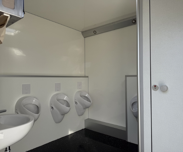 Vier Urinale und Waschbecken im Herrenbereich des Toilettenwagens 4&1 von PZV Elting Emsdetten mit separater WC-Kabine