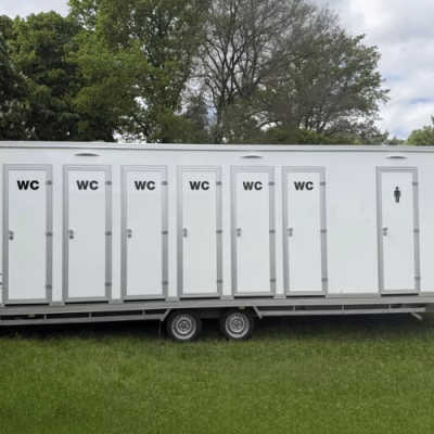 Zweite Außenansicht des Toilettenwagens XXL von PZV Elting mit zwölf Türen, geeignet für Unisex-Nutzung bei Großveranstaltungen, aufgestellt auf einer Wiese.